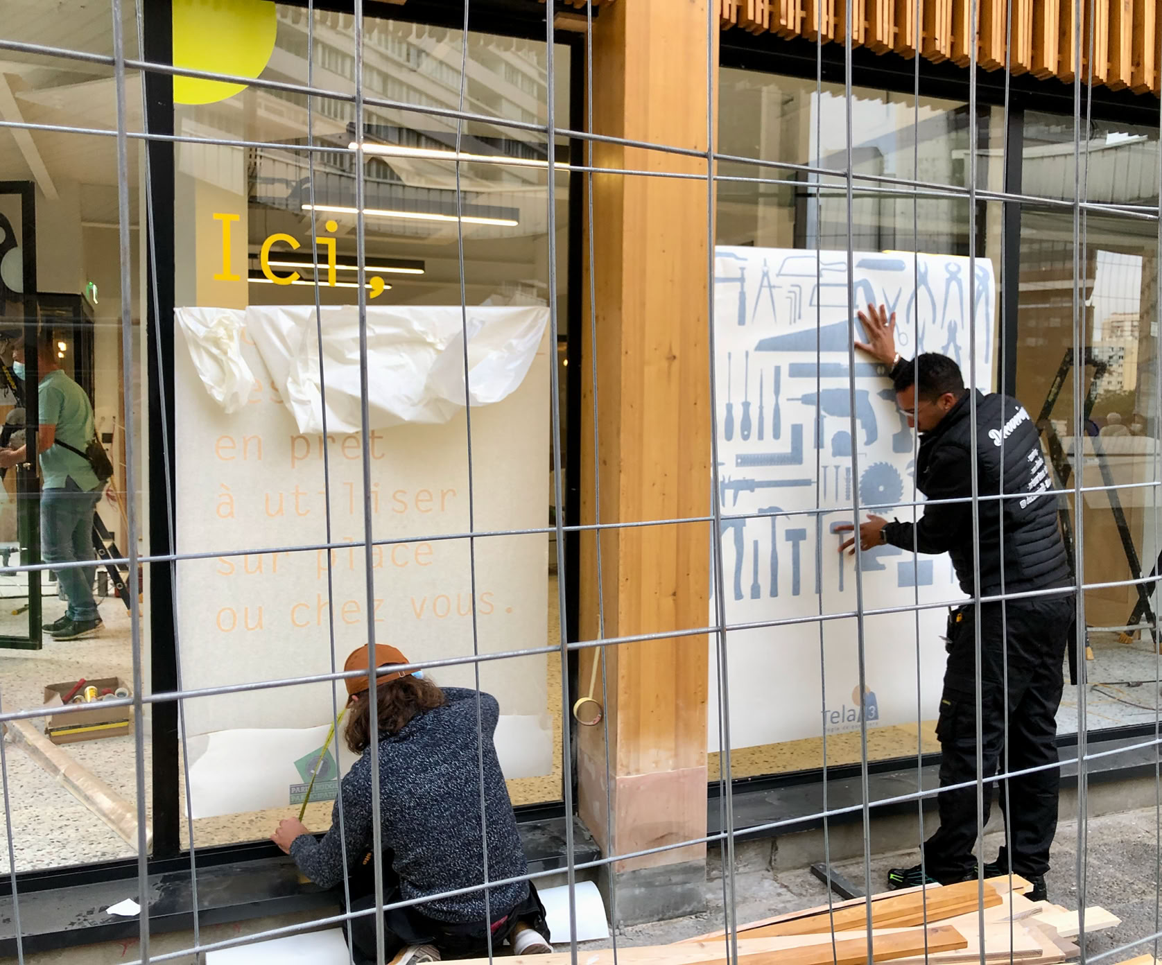 Pose de la signalétique des vitrines TELA 13, la régie de quartier.